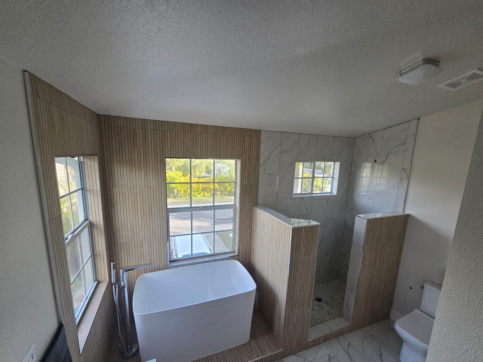 Master bathroom with a freestanding soaking tub, fluted tile, and walk in shower