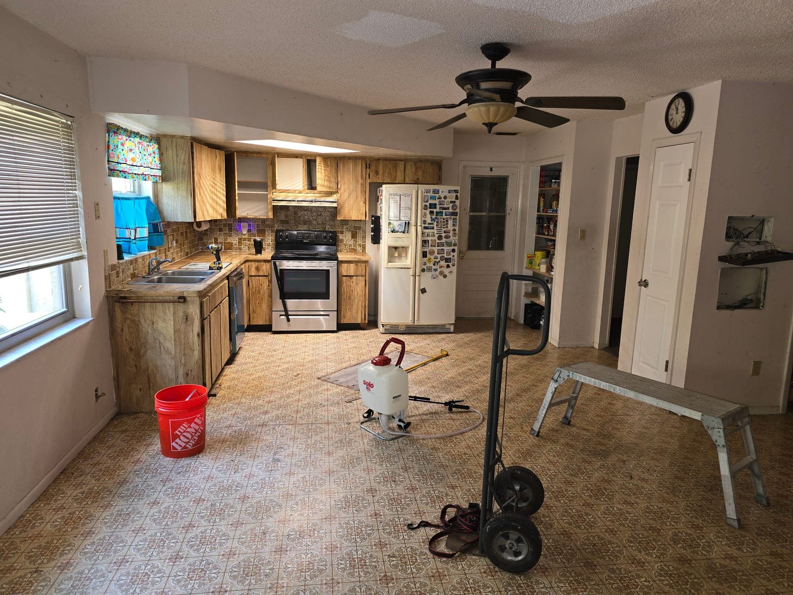 Kitchen before renovation with dated pine cabinets, laminate countertops, and patterned vinyl flooring